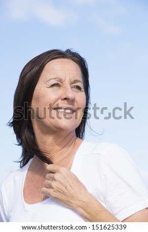 Portrait attractive mature woman joyful and happy relaxed retired, keeping healthy and fit, isolated on blue sky background.