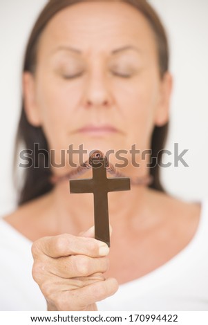 Portrait woman in blurred background holding religious symbol of crucifix in hand.