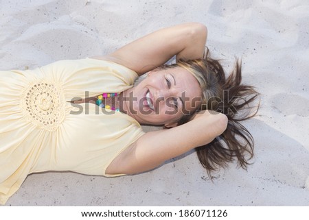 Portrait attractive relaxed mature woman lying happy smiling on sandy beach, with hands behind neck, enjoying retirement, copy space.
