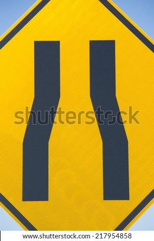 Street sign indicating narrow road ahead, caution driver to slow down.