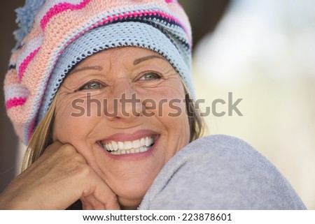 Portrait attractive mature woman with beanie hat to keep warm in winter, happy relaxed smiling, blurred background outdoor.