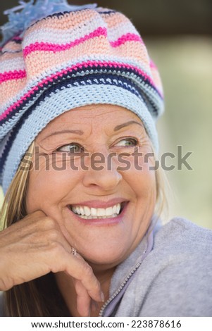 Portrait attractive mature woman with beanie hat to keep head warm in winter, happy relaxed smiling, blurred background outdoor.