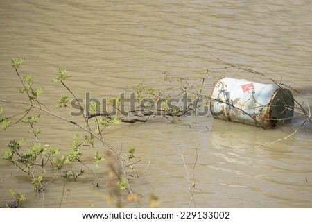 Rusty corroded barrel of toxic industrial chemical liquid dumped in water of river or lake, hazard for natural environment and ecology, copy space.