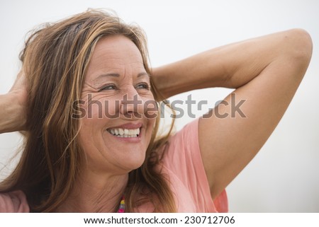 Portrait attractive mature woman posing happy joyful smiling with hands behind neck, enjoying active retirement, bright background and copy space.