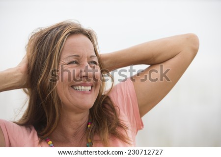 Portrait attractive mature woman posing happy joyful smiling with hands behind neck, enjoying active retirement, white background and copy space.