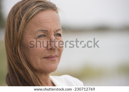 Portrait attractive mature woman outdoor looking confident happy and relaxed, with bright blurred background and copy space.