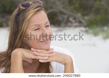 Portrait attractive mature woman sitting happy healthy dreaming outdoor, peaceful and relaxed with chin rested on hands, blurred background and copy space.