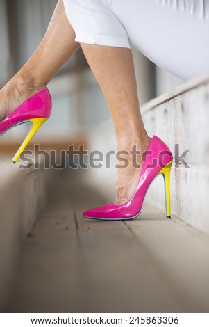 Concept detail image of woman sitting in Elegant sexy pink high heel shoes, sitting relaxed on bench, copy space, blurred background