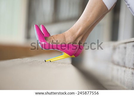 Concept detail close up image of woman sitting in Elegant sexy pink high heel shoes,  relaxed on bench, copy space, blurred background