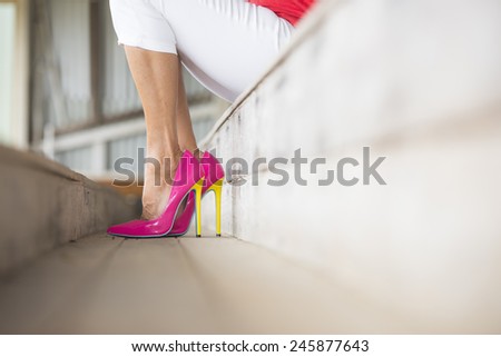 Concept close up image of woman sitting in Elegant sexy pink high heel shoes, relaxed on bench, copy space, blurred background.