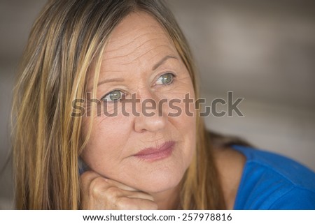 Portrait attractive mature woman with thoughtful serious facial expression, relaxed, laid back, peaceful daydreaming, blurred background.