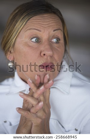 Portrait attractive mature woman with surprised anxious facial expression, blurred background.