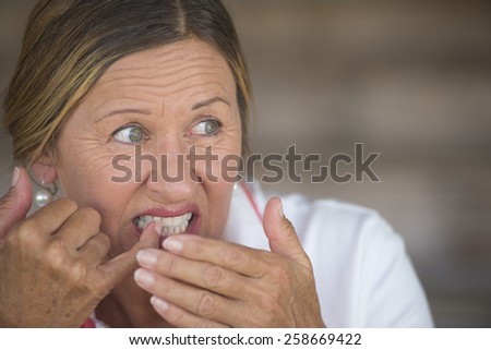 Portrait attractive mature woman in pain with toothache, stressed and unhappy facial expression, blurred background, copy space.