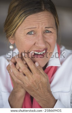 Portrait attractive mature woman in pain with toothache, stressed and unhappy facial expression, blurred background.