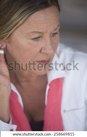 Portrait elegant attractive mature woman with sad lonely concerned depressed expression, blurred background.