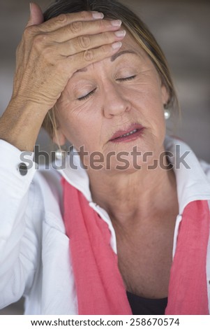 Portrait attractive mature woman with headache, painful migraine, stressful menopause, closed eyes, blurred background.