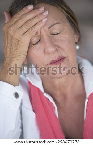 Portrait attractive mature woman with headache, migraine, stressful menopause, closed eyes, blurred background.