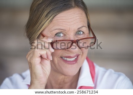 Portrait smart attractive mature business woman with glasses and happy smiling expression, blurred background.