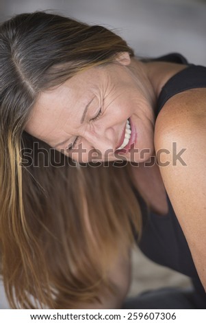 Portrait attractive mature woman smiling laughing joyful happy relaxed, closed eyes, blurred background.