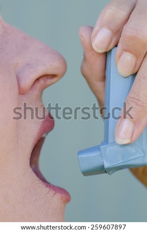 Close up detail image of woman using inhaler to help, support asthma or general breathing problem.