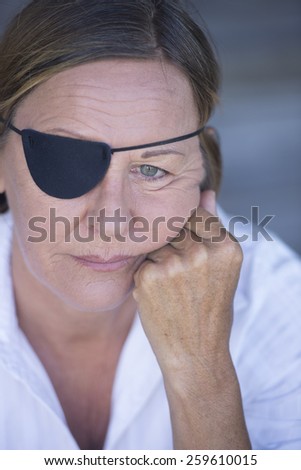 Portrait sad attractive mature woman wearing eye patch as protection after injury, closed eyes, blurred background.