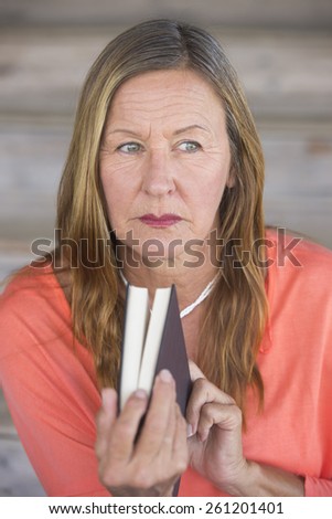 Portrait thoughtful attractive mature woman reading a book for relaxing entertainment, inspiration, blurred background.
