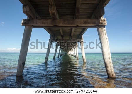 Long wooden pier at scenic tranquil ocean, with blue sky, panoramic view to horizon, copy space.