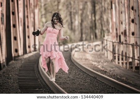Girl in a dress walking the rail line