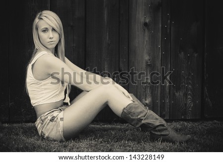 Black and white photo of a young girl sitting and posing in western wear