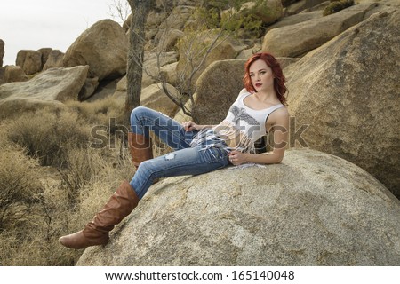 Beautiful teen girl laying on the rock and posing in large boots