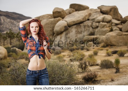 Young model wearing red plaid shirt and low-rise jeans posing at Joshua Tree National Park