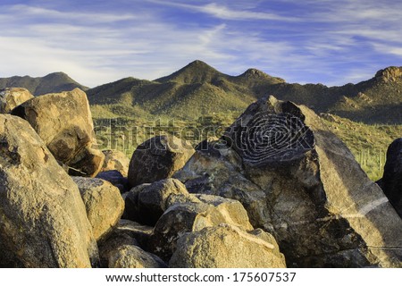 Boulders with indian art drawings with mountains and sky in the background