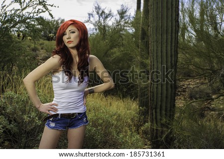 Sassy redhead model posing outdoors in the desert wearing jeans cut off shorts