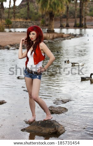 Skinny and slim young model posing in a red vest and red hair with long legs