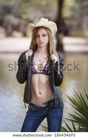 Young cowgirl wearing cowboy hat and jeans with unzipped jeans