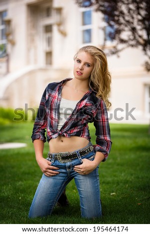 American and country western girl posing outdoors in jeans and flannel shirt