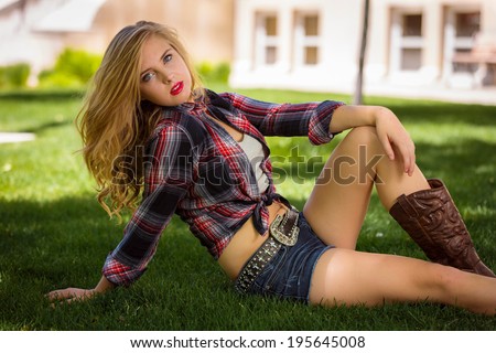 Gorgeous and young lady posing outdoors in flannel shirt and denim shorts