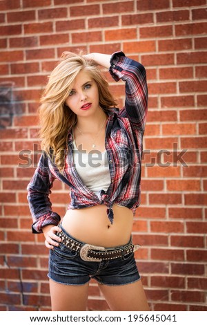 Sassy teen girl in flannel shirt and low rise jeans shorts