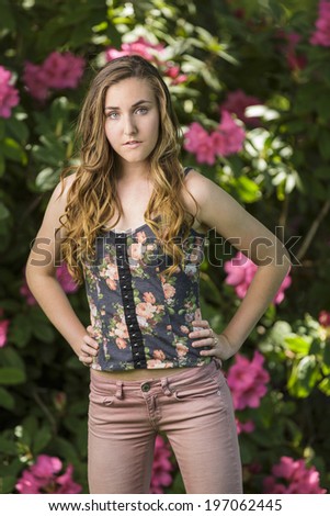 Young female model posing in pink denim with flowers in the background