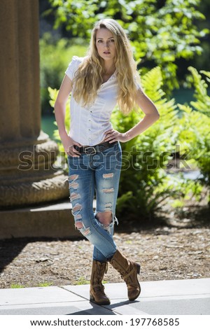 Full body portrait of a young blond girl in ripped jeans and boots