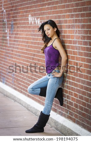 Young latino petite female model in purple shirt and jeans and tall boots