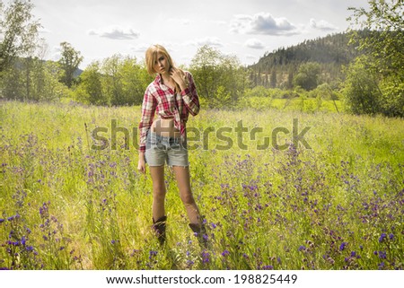 Young girl in red flannel shirt and denim shorts posing in the purple flower field