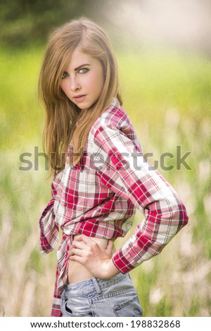 Gorgeous and young girl wearing tied red flannel shirt with sun flare