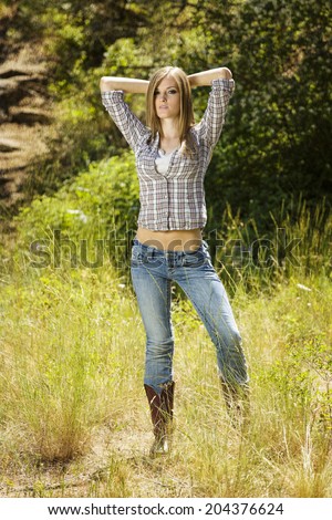 Beautiful and young gal in western flannel shirt and tight jean pants