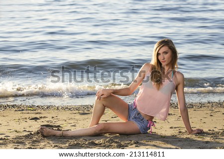 Full body of a young female model in pink top and jeans shorts