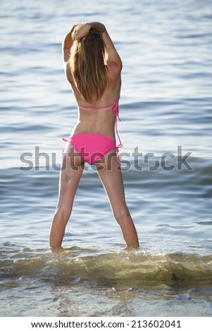 Young model posing in pink bikini swimwear from behind
