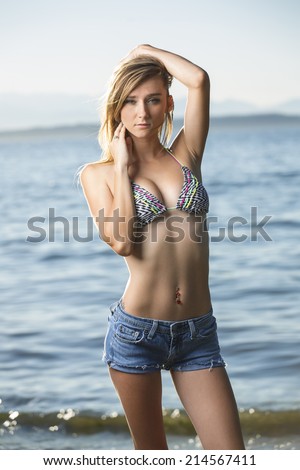 Sassy and young blonde girl in bikini top and low rise jeans shorts