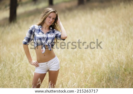 Young model posing in white shorts and flannel shirt in the field