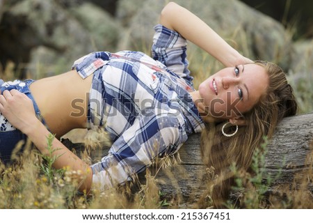 Beautiful and young girl laying on the ground and posing in blue flannel shirt with a sassy smile