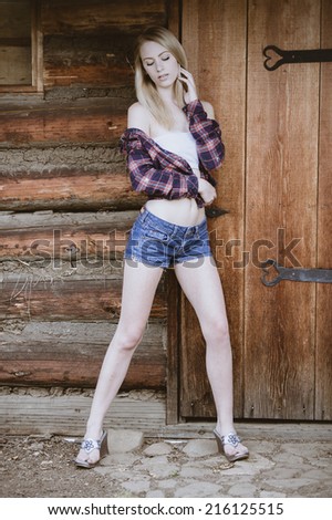 Full body western portrait of a girl in denim shorts and red flannel long sleeve shirt